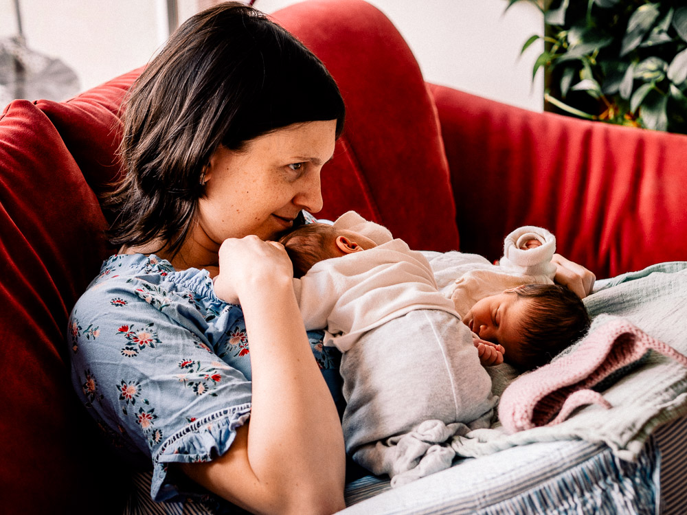 Mutter sitzt mit Baby Zwillingen auf der Couch und genießt den Moment