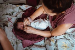 Mutter zieht frisch geborenes Baby an