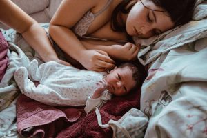 Schwester kuschelt mit neugeborenem Baby