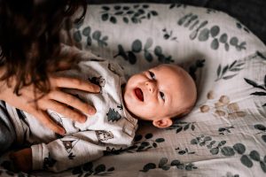 Baby frisch geboren im Wochenbett mit Hand der Mutter auf dem Bauch