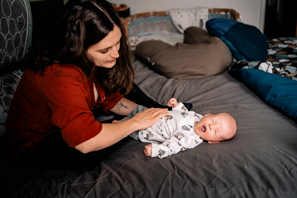 Mutter schaut auf Neugeborenes welches gähnt