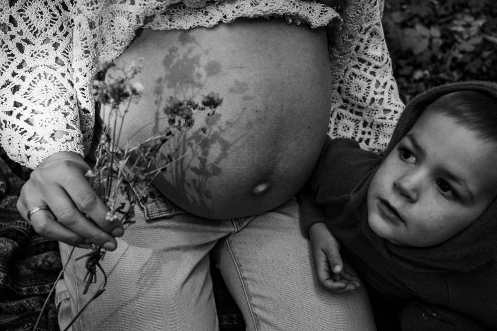 Schattenbild mit Blumen auf Babybauch bei dokumentarischen Fotogshooting