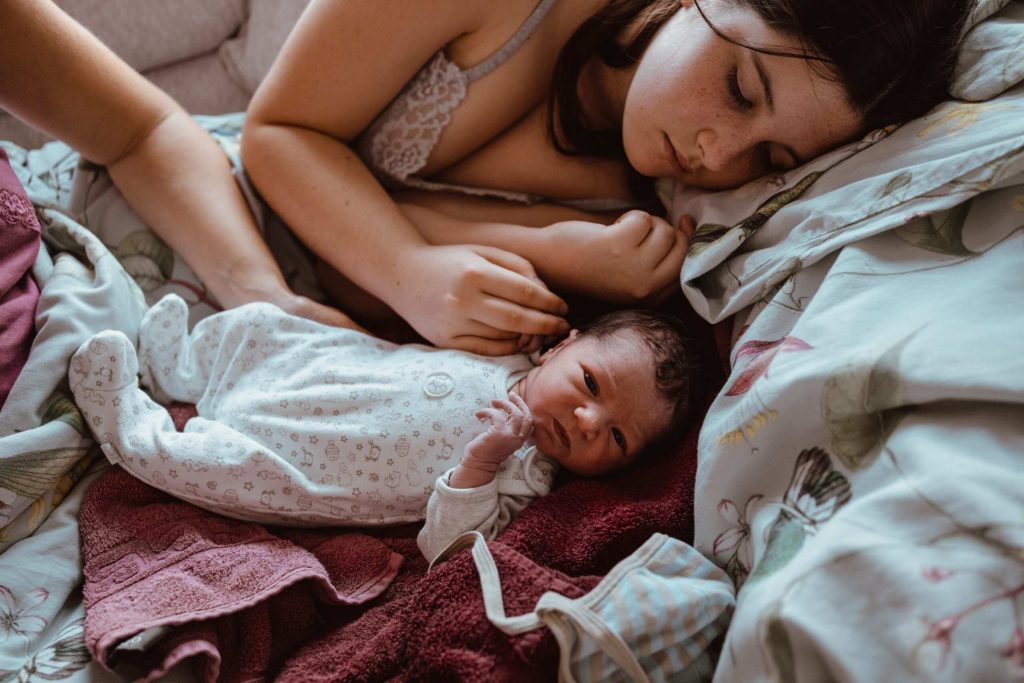 Schwester kuschelt mit neugeborenem Baby